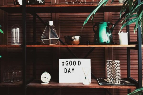 Modern interior shelf rack with assorted decorations and glowers and light box with tag Good day
